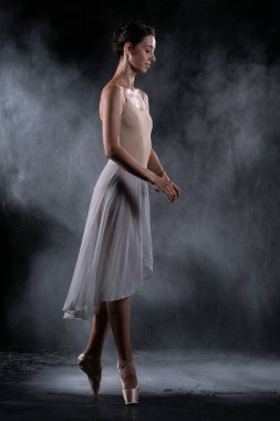 Siyah duvarın yanındaki stüdyoda dans eden balerin.