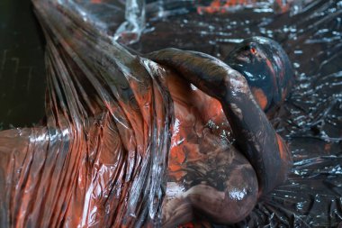 Çıplak kadın üzerine siyah ve turuncu boya dökülmüş.