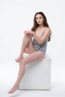 Stüdyoda gri bir tişörtle poz veren genç ve güzel bir kadın.