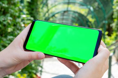 Modern smartphone bir park mockup tutan kadın