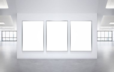 Ofis duvarında asılı üç beyaz dikey çerçeve. Modern şirket içi reklam panolarının taklidini yap.