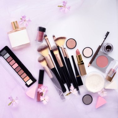 Çiçekli pembe peçe arka plan üzerinde Dekoratif kozmetik ve makyaj fırça. Üstten görünüm