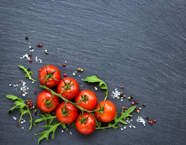Görünümü taze kiraz domates, tuz, biber ve roka yaprağı siyah arduvaz tahtası, top