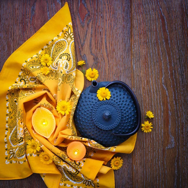 铁蓝色茶壶与黄色菊花花和蜡烛在木质背景 顶部视图 — 图库照片