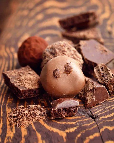 Handmade chocolate candies and pieces of chocolate on wooden background