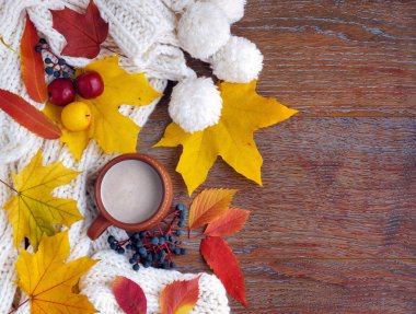 Sonbahar kompozisyon. Bir fincan kahve, renkli yaprakları ve eşarp ahşap arka plan üzerinde. Üstten görünüm. Senin metin için yer.