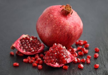 Olgun nar ve tohumlar siyah taş zemin üzerine dağılmış