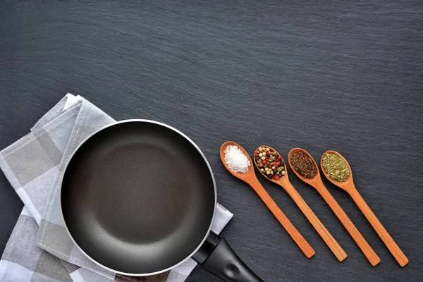 Empty frying pan with napkin and spices on dark grey stone — Stock Photo, Image