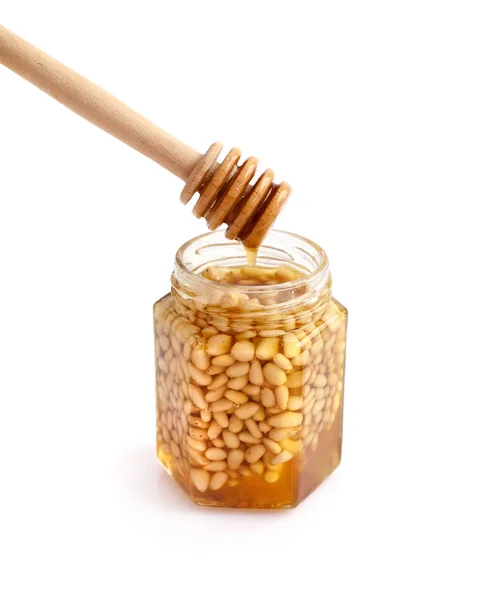 Een pot honing met pijnboompitten en een lepel voor honing — Stockfoto