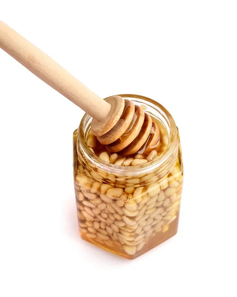 Un tarro de miel con piñones y una cuchara para miel — Foto de Stock