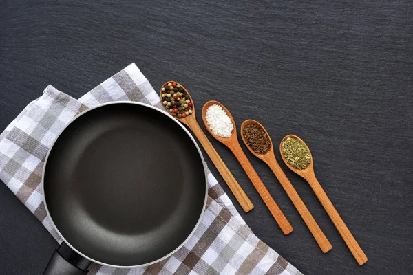 Empty frying pan with napkin and spices on dark grey stone — Stock Photo, Image