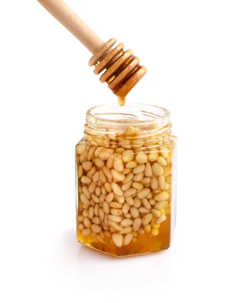 A honey jar with pine nuts and a spoon for honey — Stock Photo, Image