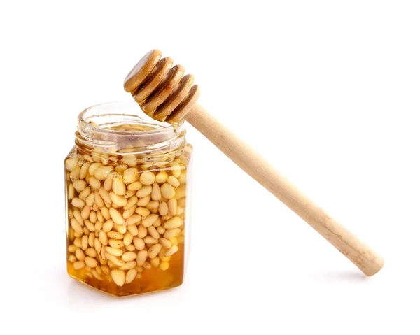 A honey jar with pine nuts and a spoon for honey on white — Stock Photo, Image