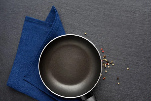 Empty frying pan with napkin on dark grey stone background. Top — Stock Photo, Image