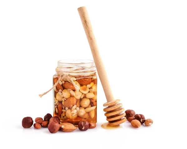 A honey jar with a spoon for honey and different nuts on white — Stock Photo, Image