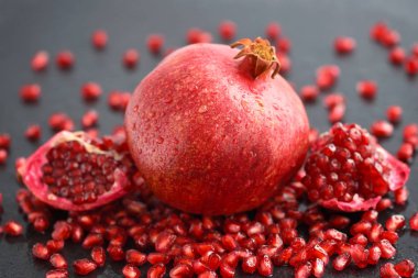 Olgun nar ve tohumlar siyah taş zemin üzerine dağılmış