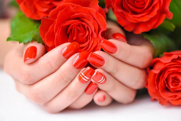 Woman beautiful hands with red manicure and scarlet roses — Stock Photo, Image