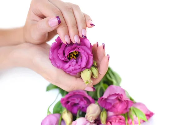 Handen van een vrouw met roze Franse manicure en bloemen eustoma — Stockfoto