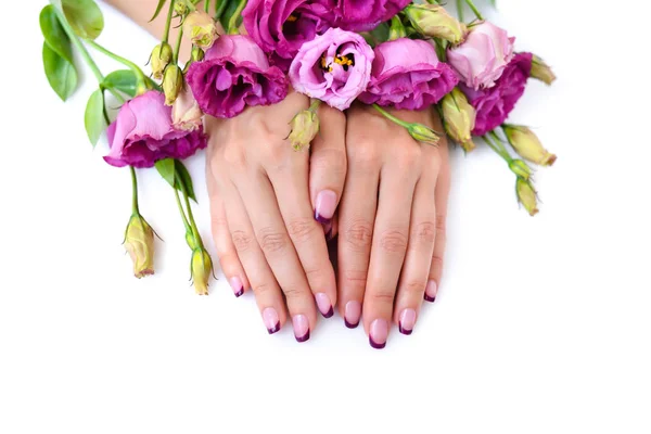 Ręce kobiety z różowy eustoma francuski manicure i kwiaty — Zdjęcie stockowe