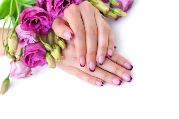 Ręce kobiety z różowy eustoma francuski manicure i kwiaty — Zdjęcie stockowe