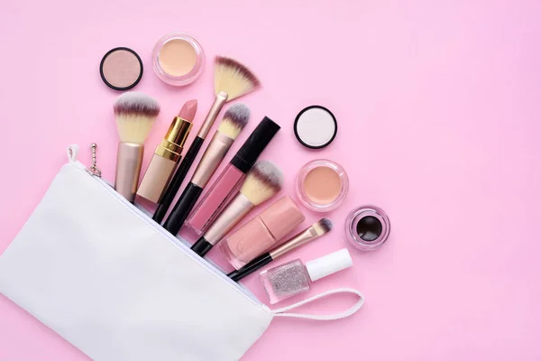 Una bolsa de cosméticos blanca con productos de maquillaje que se derraman en un — Foto de Stock