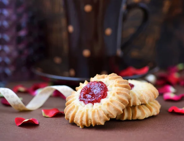 Biscuits sablés avec confiture au milieu sur plaque sur fond brun — Photo