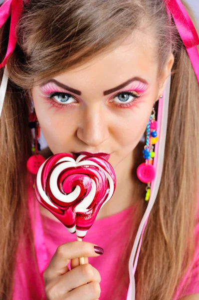 Mooie vrouw met creatieve make-up bijten kleurrijke lollipop — Stockfoto