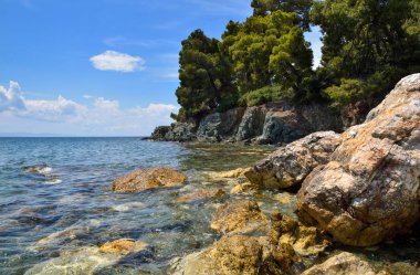 Taşları ve şeffaf mavi suyu olan güzel bir deniz manzarası.