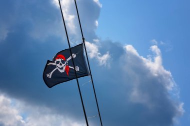 Jolly Roger - Bir Korsan kafatası bayrağı ve çapraz kemikler korsan bayrağı rüzgarda sallayarak