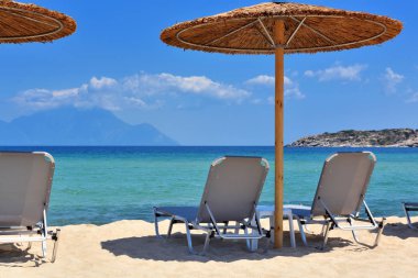 Kumsaldaki şemsiye ler ve sandalyeler. Plajdan deniz manzarası