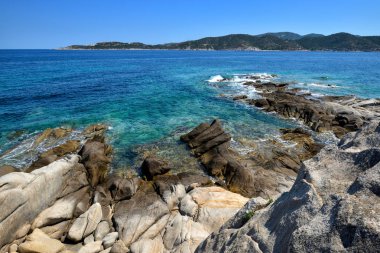 Taşları ve şeffaf mavi suyu olan güzel bir deniz manzarası.