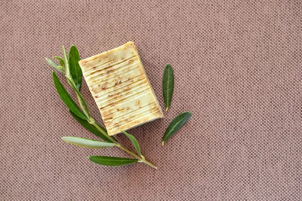 Natürliche Olivenseife und Olivenzweig auf Stoffhintergrund. — Stockfoto