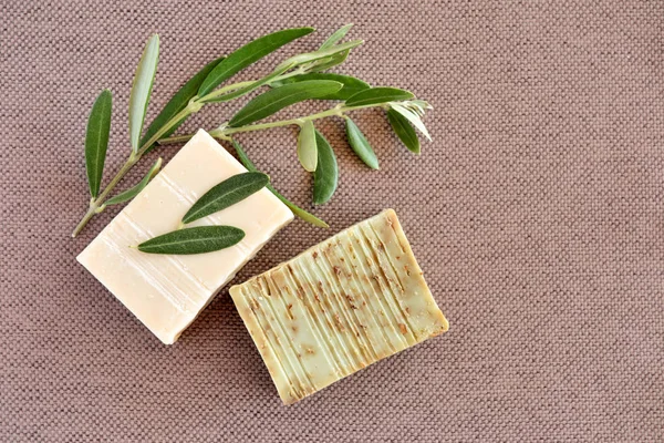 Handmade soap bars and olive branches on fabric background. — Stock Photo, Image