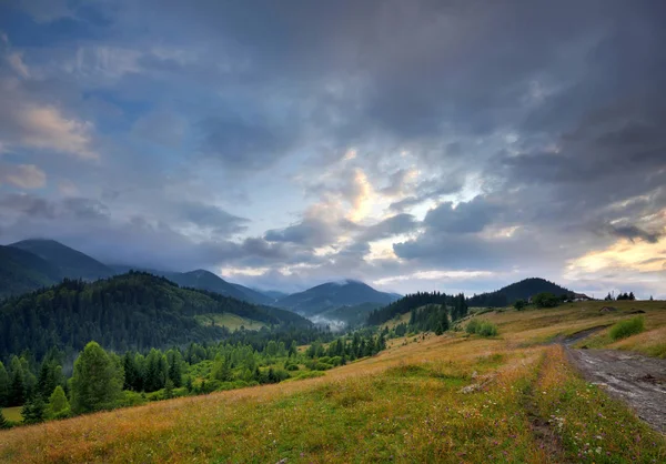 Paisagem de montanha incrível com nevoeiro e com uma estrada de terra . — Fotografia de Stock