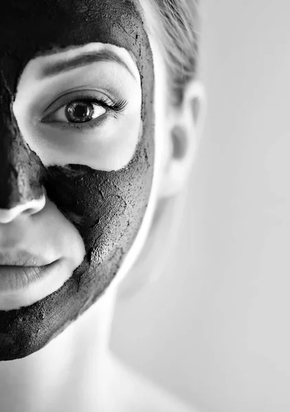 Beautiful girl with mask from clay on his face. Cosmetic mask. Beauty face. Beauty wellness concept. Black&white photo