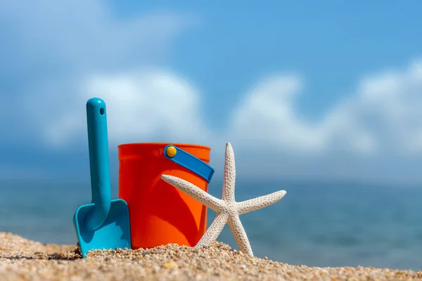 Children's beach toys - buckets, spade and starfish on sand — Stock Photo, Image