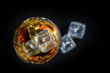 Bir bardak viski ya da siyah arka planda buz küplü diğer alkoller.