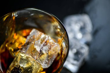 Bir bardak viski ya da siyah arka planda buz küplü diğer alkoller.