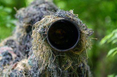 Vahşi doğada çalışan, yazın giydiği kamuflaj kıyafetiyle vahşi yaşam fotoğrafçısı.