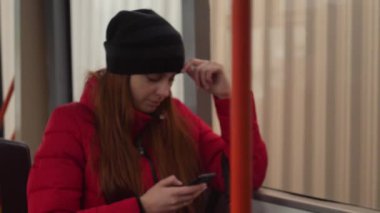 Cep telefonu üzerinde otobüs yolculuğu akşam sırasında konuşurken Genç beyaz kadın. Ufuk kentsel trafik otobüs pencere yavaş 4k vurdu