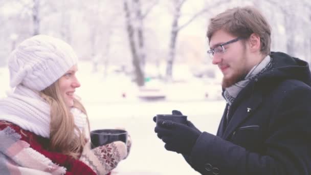 Boldog kaukázusi fiatal férfi és a nő kezében egy havas parkban beszél kávéval — Stock videók