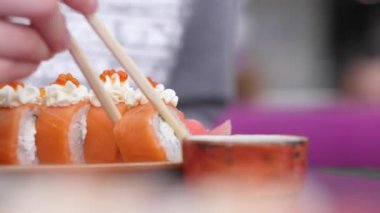 Kadın el suşi Roll soya sosu içine daldırma çubukları ile. Clouse kadar. 4k ile somon suşi Japon restoran yemek kız.