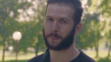 Yakın çekim kamera seyir ve gülümseyen Genç sakallı adam portresi. 4 k ön görünüm slowmo