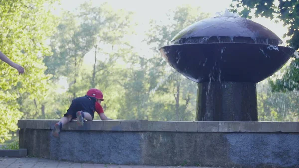küçük bebek, Çeşme ve onu korumak için onun oğlu tutan annenin kenar üzerinde tırmanmaya çalışıyor. 4 k yavaş mo görüntüleri