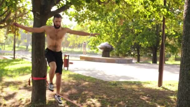 Jovem barbudo começa a andar no slackline 4K slow mo footage — Vídeo de Stock