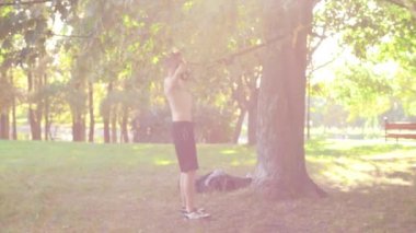 yavaş çekim yapan Pull-up fitness üzerinde parlak bir güneş Park'ta döngüler genç adam sakallı. 4 k yan görünümü görüntüleri.