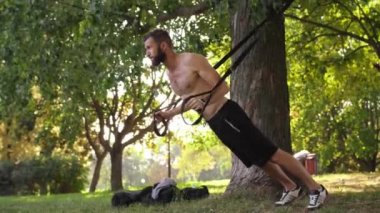 genç atlet fitness döngüler bir ağaç parkta yakınındaki şınav yapma sakallı. 4 k yavaş mo görüntüleri