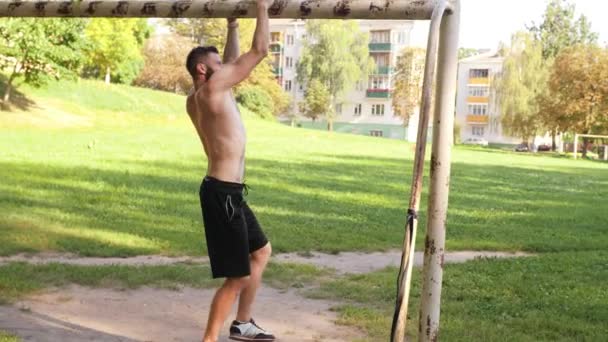Бородатый спортсмен делает упражнения на перекладине футбольных ворот. Съемка замедленного видео бокового вида в 4K — стоковое видео