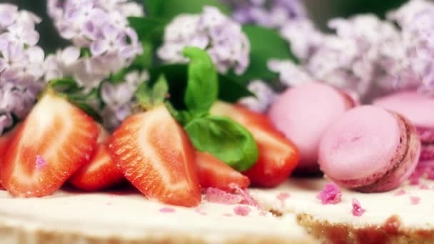 Kuchen mit einem Ausschnitt verziert mit Makronen, Erdbeeren und Blumen, 4k slow mo close up — Stockvideo