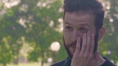 Genç bir sakallı adam losyonları portresi göz ve sonra görünüyor kamera yaptı. 4 k yakın çekim önden görünüm slowmo